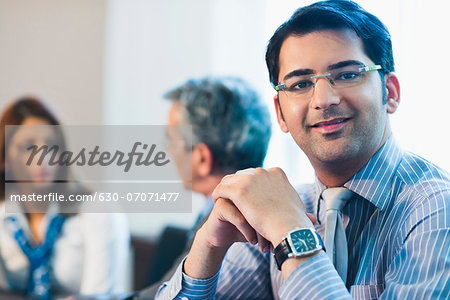 Portrait of a businessman smiling with his colleagues discussing in the background