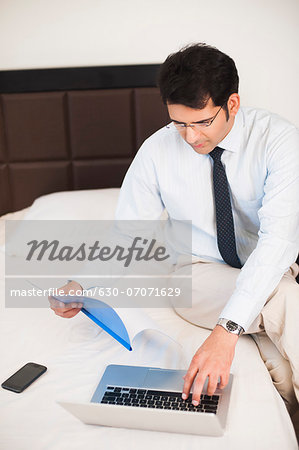 Businessman holding a file and working on a laptop