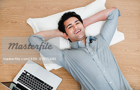 Man relaxing with a laptop beside him