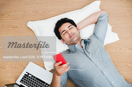 Man listening to music with a laptop beside him