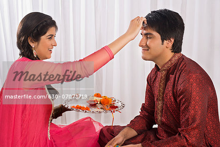 Teenage girl applying tilak to her brother at Raksha Bandhan