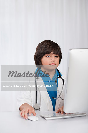 Boy using a desktop computer and imitating like a doctor