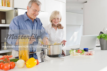 Senior couple preparing healthy pasta meal in kitchen