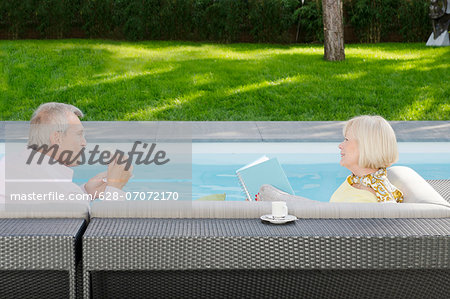 Senior couple drinking espresso by the poolside