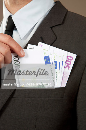 Businessman grasping in jacket pocket with Euro notes