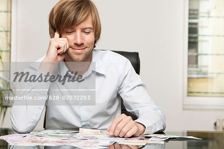 Smiling man at desk looking at banknotes
