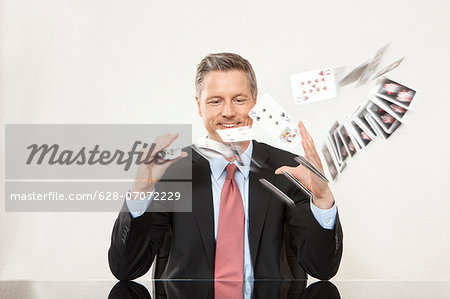 Smiling businessman playing with cards at desk