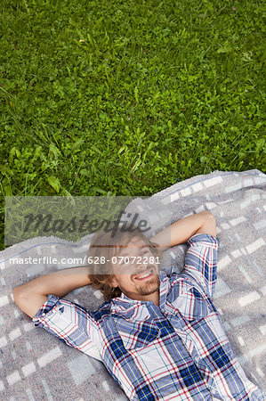 Young man relaxing on blanket in meadow