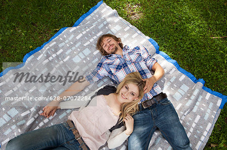 Young couple relaxing on blanket in meadow