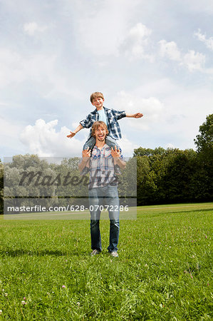 Father carrying son on shoulders outdoors