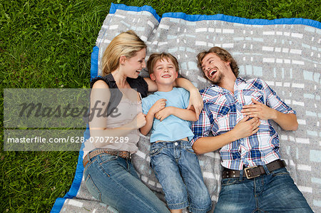 Happy family lying on blanket in meadow