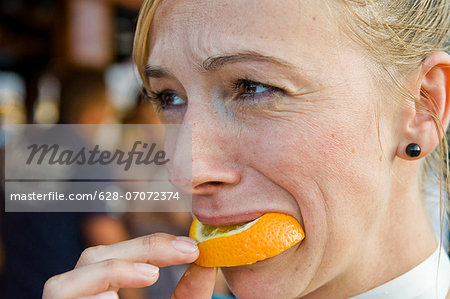 Woman biting on orange slice on the Oktoberfest in Munich, Bavaria, Germany