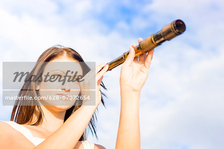 Brunette young woman looking through telescope