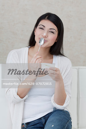 Dark-haired young woman eating yogurt