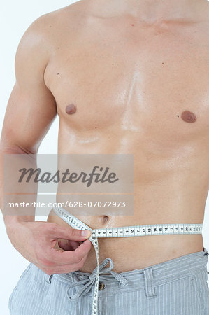 Young man measuring his waist