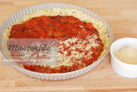 Spreading the pureed tomatoes on the shortbread pastry in the mould and sprinkle with parmesan