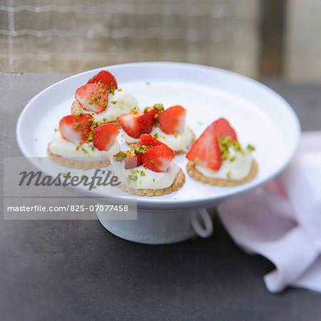 Shortbread cookies topped with cream,strawberries and pistachios