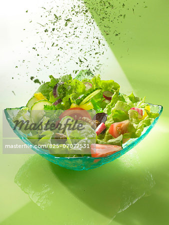 Sprinkling a mixed salad with herbs