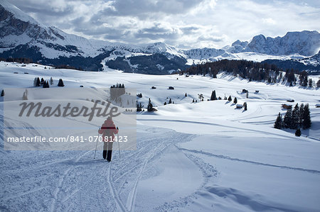 A woman walking on a snowy hiking trail in the Alpe di Siusi Ski resort near the town of Otisei in the Dolomites, South Tyrol, Italy, Europe