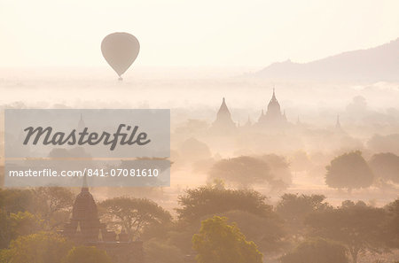 View over the temples of Bagan swathed in early morning mist, with hot air balloon drifting across the scene, from Shwesandaw Paya, Bagan, Myanmar (Burma), Southeast Asia
