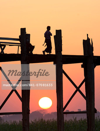 Local man walking on the famous U Bein teak bridge at sunset, near Mandalay, Myanmar (Burma), Asia