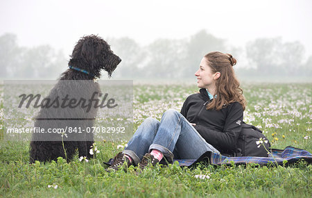 Young woman smiling at Labradoodle pet dog, Wiltshire, England, United Kingdom, Europe