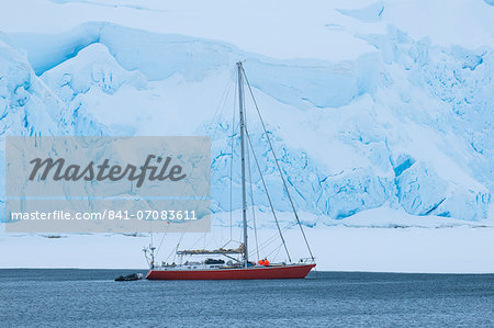 Sailing boat below a huge icefield near Port Lockroy research station, Antarctica, Polar Regions Sailing boat below a huge icefield near Port Lockroy research station, Antarctica, Polar Regions