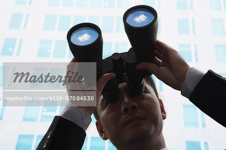 Close-Up of Young Businessman Using Binoculars and Looking