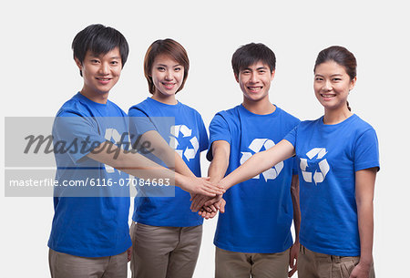 Four young people in recycling t-shirts with hands together, studio shot