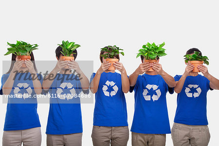 Group of people holding plants, obscuring faces, studio shot