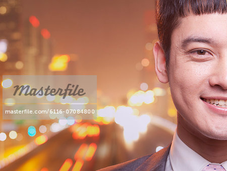 Close-up of smiling young business man, city lights background