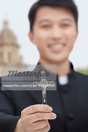 Young Priest Holding Crucifix, Looking at Camera