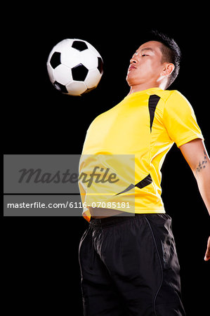 Footballer chesting ball, black background