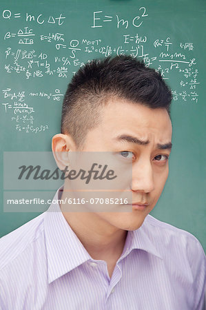 Young student in front of blackboard, making a face, portrait