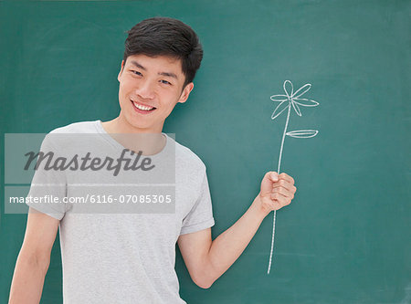Portrait of young man in front of chalkboard with flower drawing