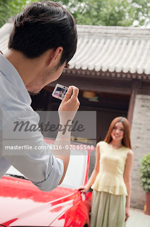 Young Man Taking a Picture of His Girlfriend and Car