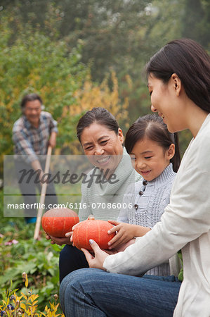 Happy family harvesting vegetables in garden