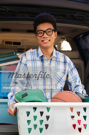 Portrait of boy with college dorm items in back of car