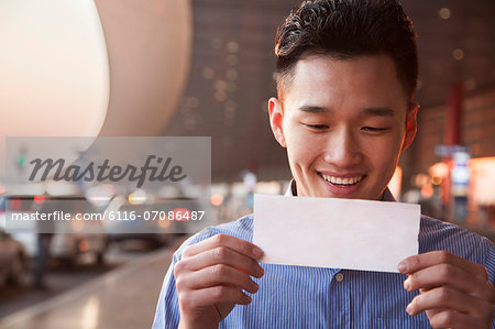 Young traveler looking at ticket at airport