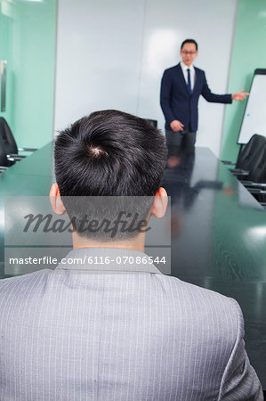 Rear View of Businessman Listening to Presentation