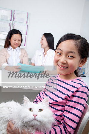 Woman and girl with pet cat in veterinarian's office