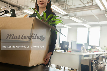Young businesswoman moving box with office supplies
