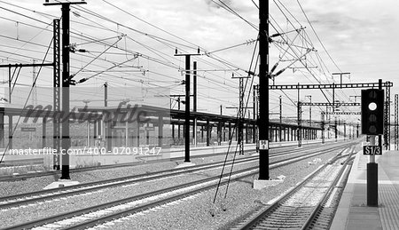 Railway with electric posts and platforms black and white
