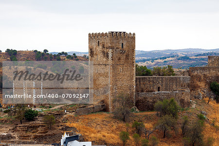 Fortified stone lookout tower with crenellations alongside a perimeter wall affording a view over the surrounding countryside and valley