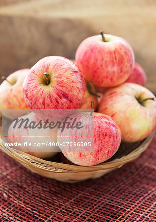 Fresh red apples in basket on the table and wooden background