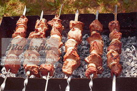 Shashlik (shish kebab) prepared on the metal skewers outdoors in summertime