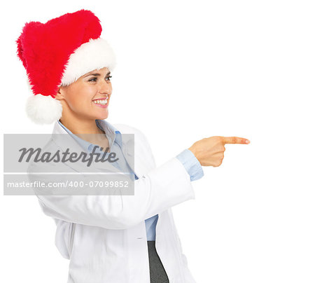 Smiling doctor woman in santa hat pointing on copy space