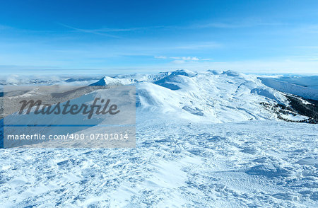 Sunny winter mountain landscape with low-hanging clouds and snowy ridge. (Chornohora , Carpathian, Ukraine).