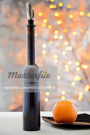 Orange on the plate and a bottle of wine on a multicolored background