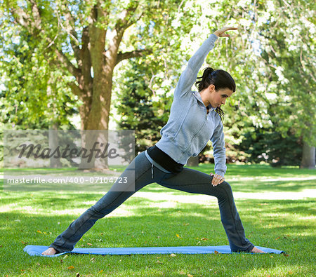 fitness model exercising yoga in the park during fall